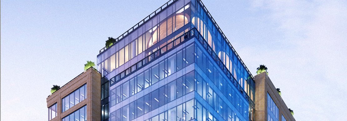 A modern glass office building with a blue tint, featuring plants on the upper terrace and soft interior lighting visible through large windows. The sky in the background is clear with a light blue hue.