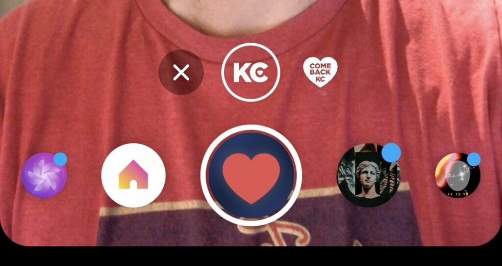 A person wearing a red shirt is partially visible in the background. The foreground shows a mobile app or social media interface with a central heart icon and several circular icons above it.