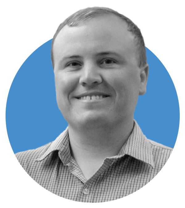 A man with short light hair smiles at the camera. He is wearing a light-colored, checkered button-up shirt. The background features a blue circle behind him with the rest in light gray.